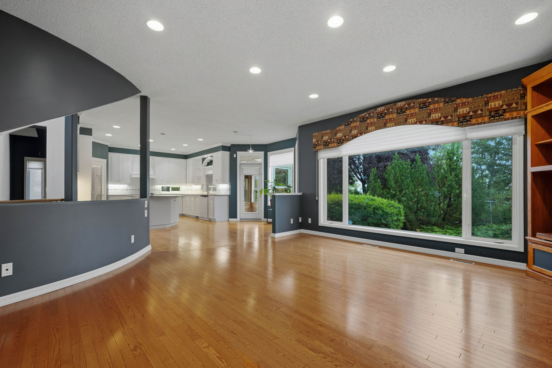 Family room with a wall of windows opening to the white kitchen beyond